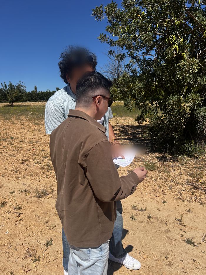 Daniel Siew examining a printed site plan while standing on the land during an on-site assessment in Valencia, Spain.